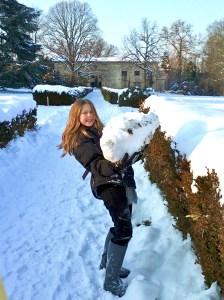 a young girl holding an enormous snow ball.